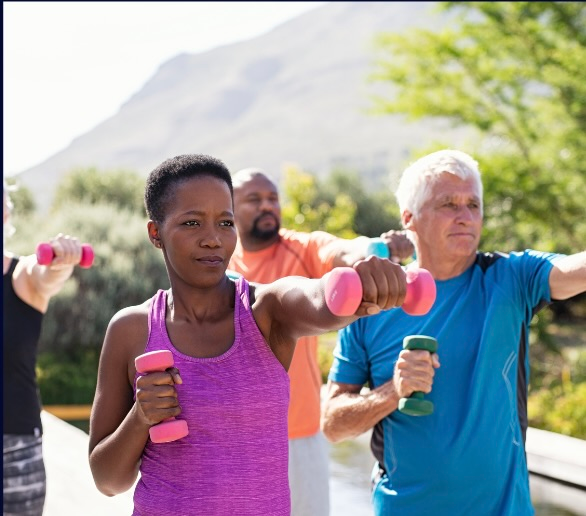 Older adults performing strength training with dumbbells outdoors to improve mobility and strength after 50